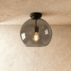 Clérachic smoked glass globe ceiling light flush-mounts with black hardware, filament bulb glowing inside.