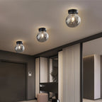Clérachic smoked glass globe ceiling lights flush-mount in a row, lighting a dark modern entry hallway.