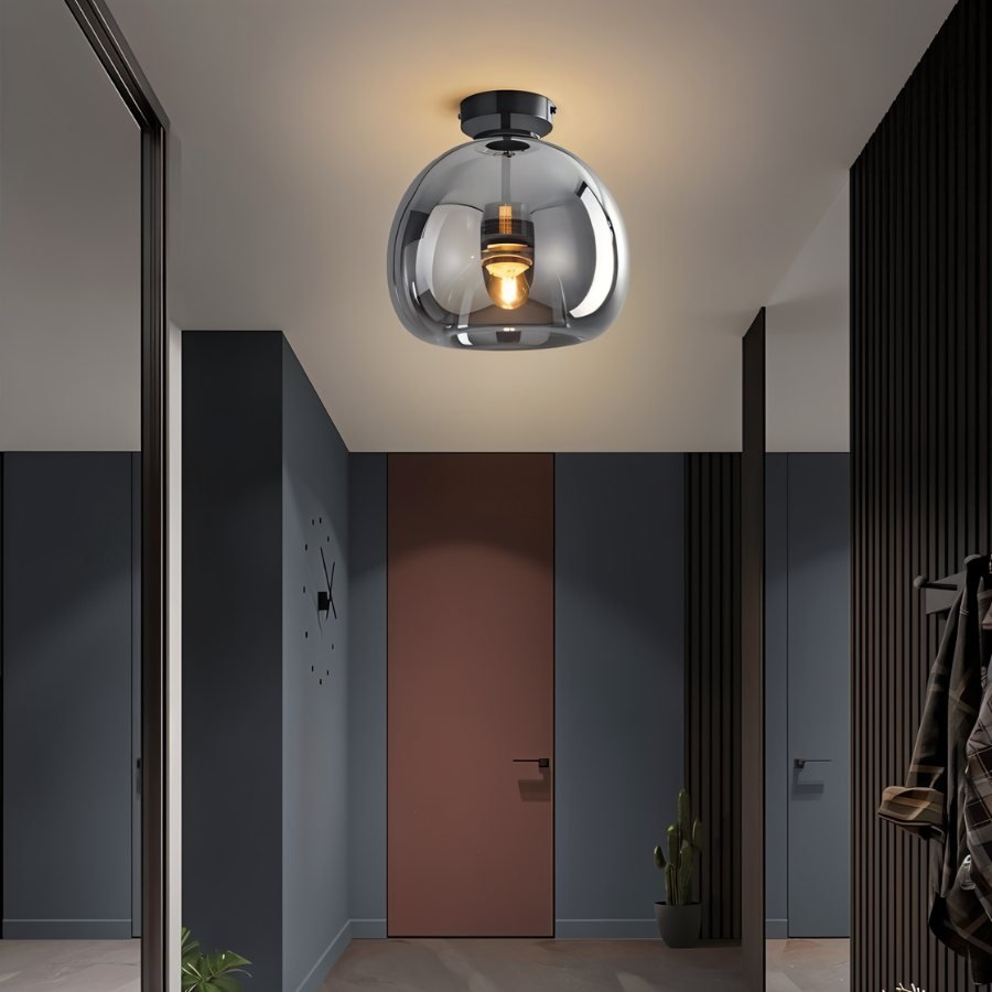 Clérachic smoked glass globe pendant hangs above a hallway with a terracotta door and slatted dark walls.