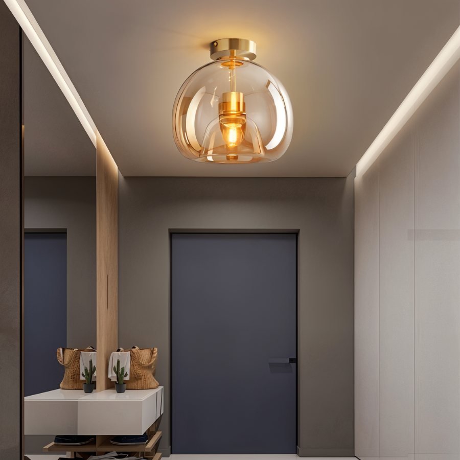 Clérachic amber glass globe pendant lights an entryway console with a mirror, bags and potted cacti below.