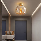 Clérachic amber glass globe pendant lights an entryway console with a mirror, bags and potted cacti below.