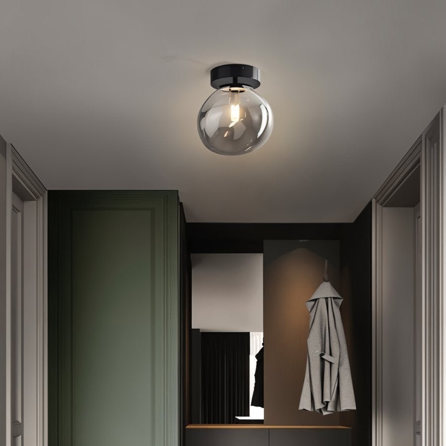 Clérachic smoked glass globe ceiling light flush-mounts above a hallway with a sage green door and mirror.