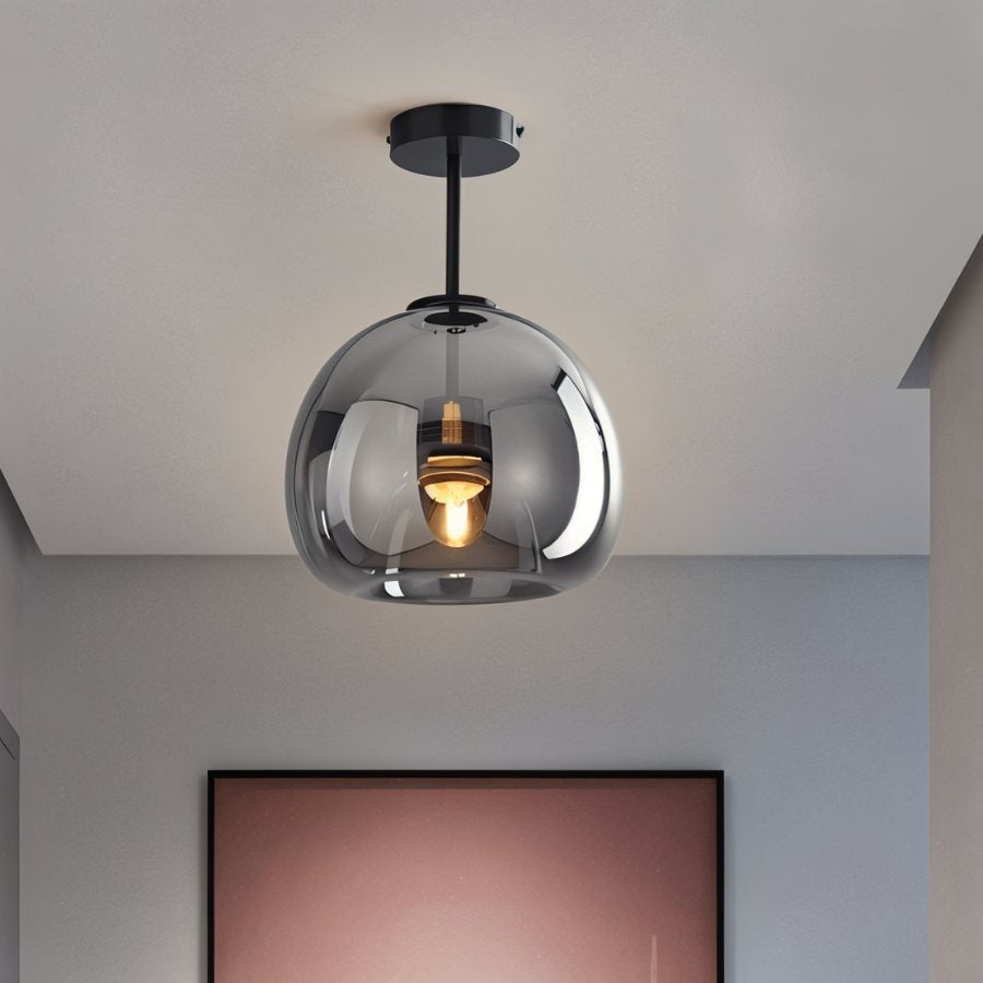 Clérachic smoked glass globe pendant hangs from a black rod above a room with a blush-toned framed artwork.