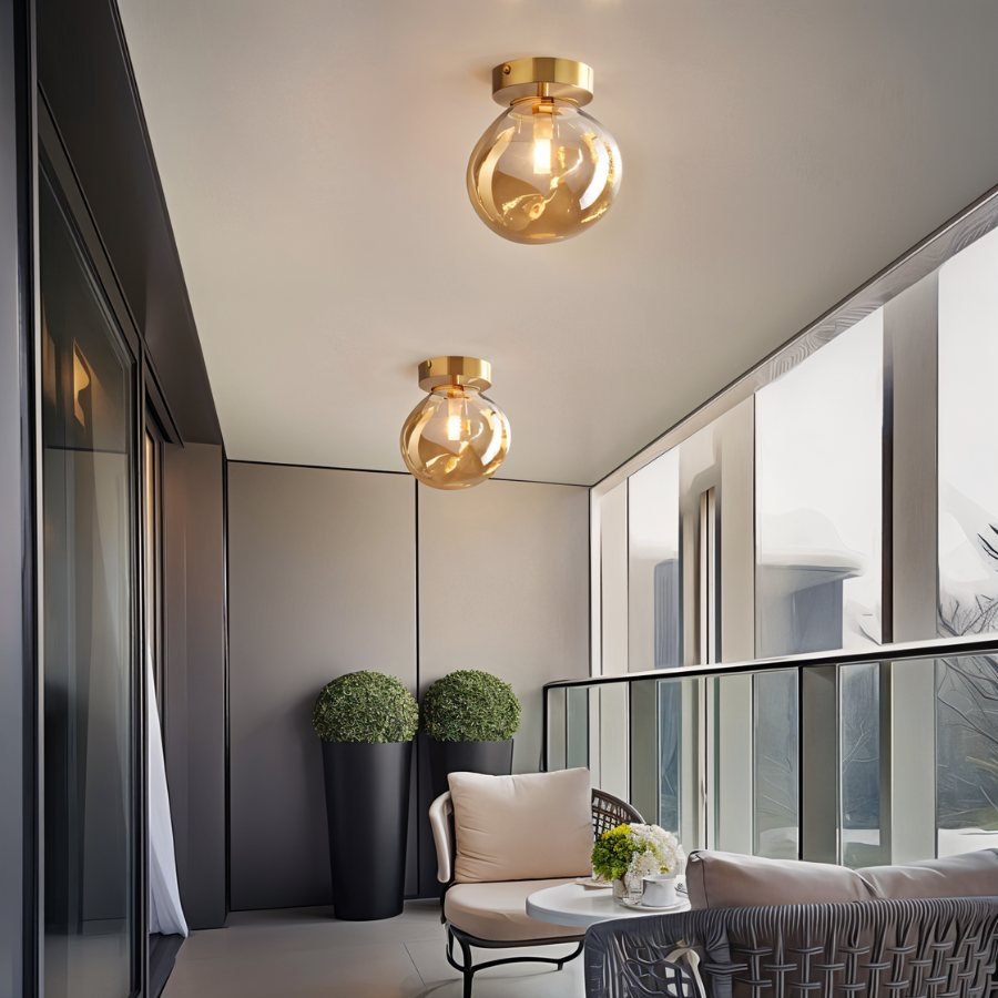 Clérachic amber glass globe ceiling lights flush-mount over a balcony seating area with potted greenery.
