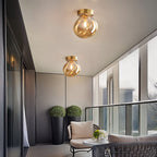 Clérachic amber glass globe ceiling lights flush-mount over a balcony seating area with potted greenery.