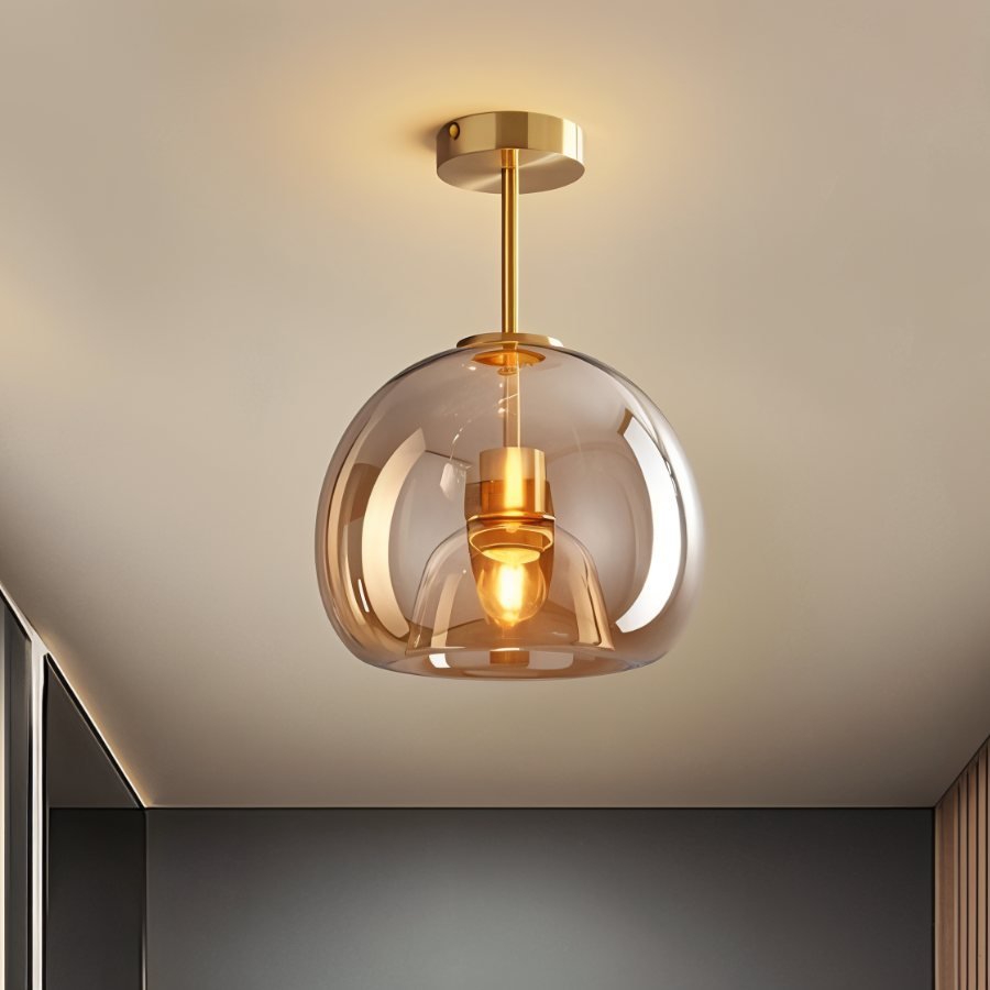 Clérachic amber glass globe pendant drops on a gold rod, lighting a hallway with a dark panelled door.