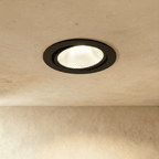 Clérachic downlight in black, its tiltable round trim recessed into the ceiling and glowing warm white.