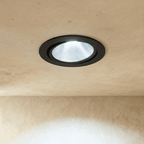 Clérachic downlight in black, the round trim casting a crisp cool-white beam against a plaster ceiling.