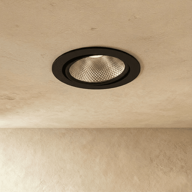 Clérachic downlight in black, its adjustable round trim glowing warm white from a textured plaster ceiling.