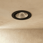 Clérachic downlight in black, its adjustable round trim glowing warm white from a textured plaster ceiling.