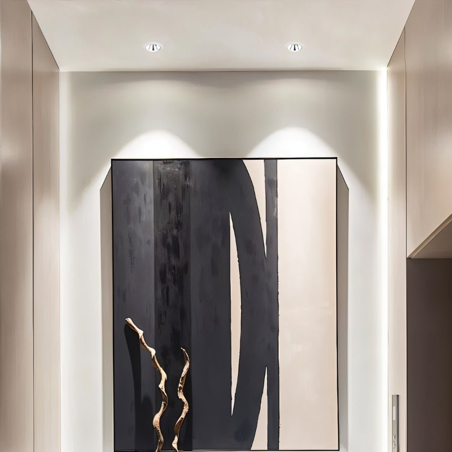 Two Clérachic downlights in white angled to wash light over a black and beige abstract painting in a hallway.