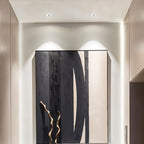 Two Clérachic downlights in white angled to wash light over a black and beige abstract painting in a hallway.