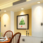 Clérachic downlights in white recessed above cream cabinetry, lighting a framed illustrated print in a dining nook.