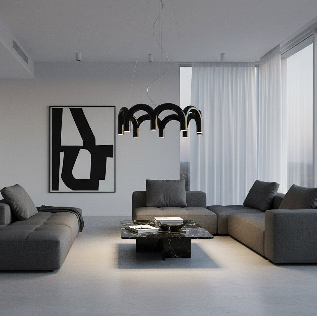 A black arched-tube Clérachic chandelier above a dark coffee table in a grey living room with a large black-and-white print.