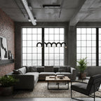 A row of black arches from this Clérachic chandelier hangs in front of tall steel windows, above a loft living room.