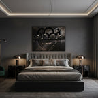 A black tiered-arch Clérachic chandelier above a bed with a grey headboard, in a dark bedroom with a lit ceiling edge.