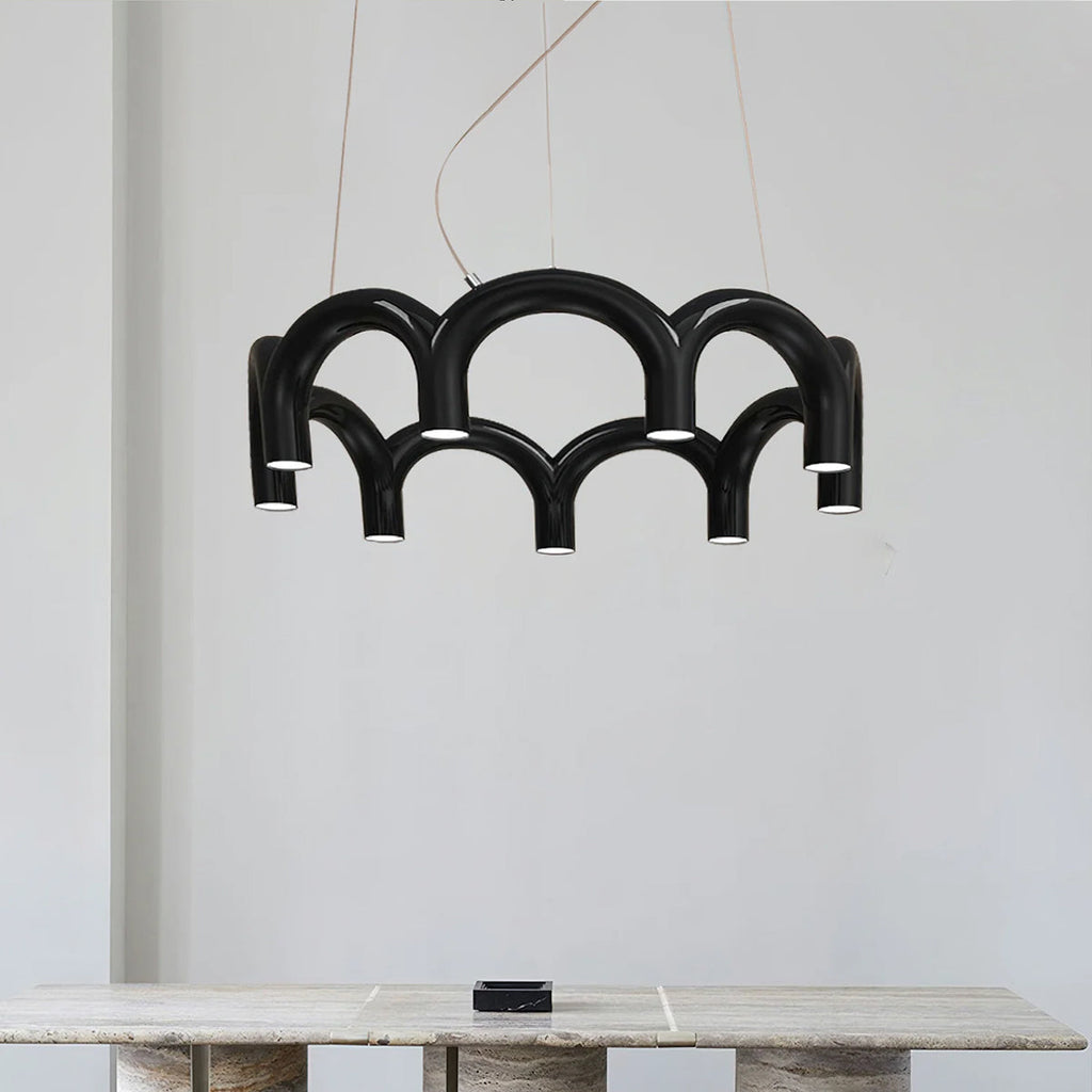 A black tiered-arch Clérachic chandelier above a travertine table, against a white wall.