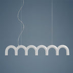 A white row of arches from this Clérachic chandelier, hung on two cables against a slate-blue backdrop.