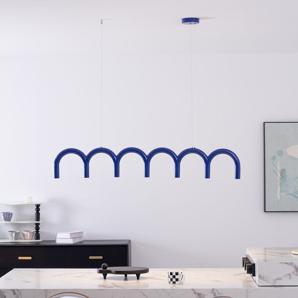 A blue row of arches from this Clérachic chandelier, hung on thin cables above a marble counter and a black sideboard.