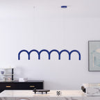 A blue row of arches from this Clérachic chandelier, hung on thin cables above a marble counter and a black sideboard.