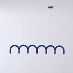 A blue row of arches from this Clérachic chandelier, with a blue canopy and thin cables, against a pale wall.