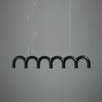 A black row of glossy arches from this Clérachic chandelier, hung on two cables, against a mid-grey backdrop.
