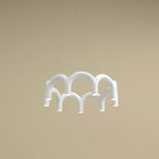 A small white tiered-arch Clérachic chandelier seen from below, against a sand-coloured backdrop.