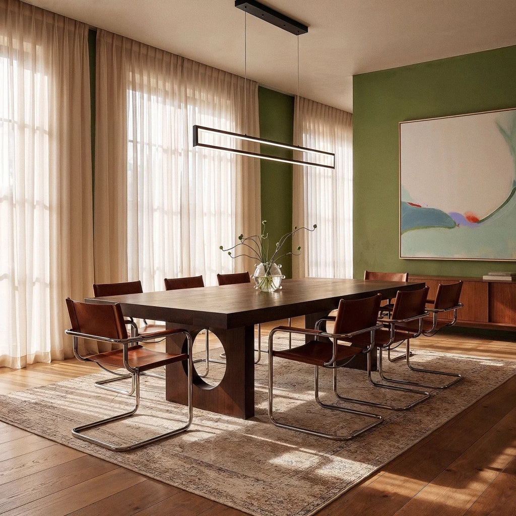 The Clérachic black frame pendant glowing warm white above a dark wood dining table against a green accent wall.