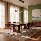 The Clérachic black frame pendant glowing warm white above a dark wood dining table against a green accent wall.