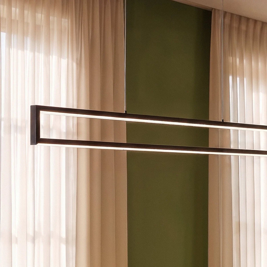 Close-up of the Clérachic black frame pendant's slim LED edges, glowing warm white against a green wall and sheer curtains.