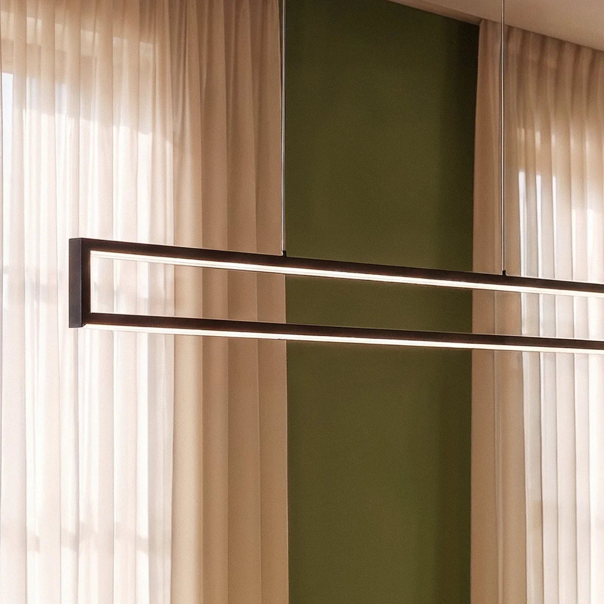 Close-up of the Clérachic black frame pendant's slim LED edges, glowing warm white against a green wall and sheer curtains.