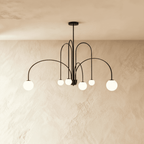 This Clérachic black Art Deco chandelier spreads its looped arms wide, each ending in a round glass globe.