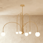 This Clérachic gold Art Deco chandelier hangs with looped brass-toned arms and six round glass globes.