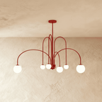 Clérachic's red Art Deco chandelier curves six arms outward, each ending in a glowing white glass globe.