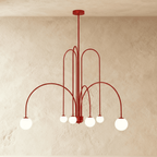 This Clérachic red Art Deco chandelier spans wide with looped arms and six round glass globe shades.