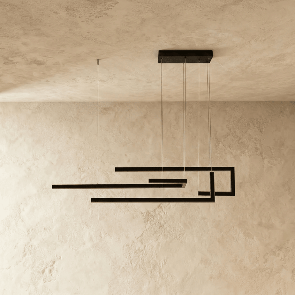Clérachic's chandelier in black, its angular linear frame glowing softly against a plastered wall.