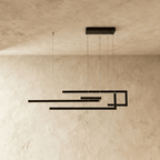 Clérachic's chandelier in black, its angular linear frame glowing softly against a plastered wall.