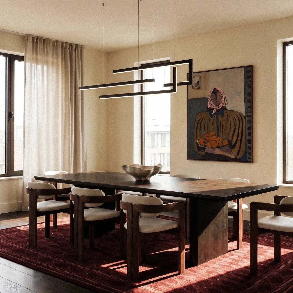 Clérachic's chandelier in black, its geometric bars glowing cool white above a long dining table and rug.
