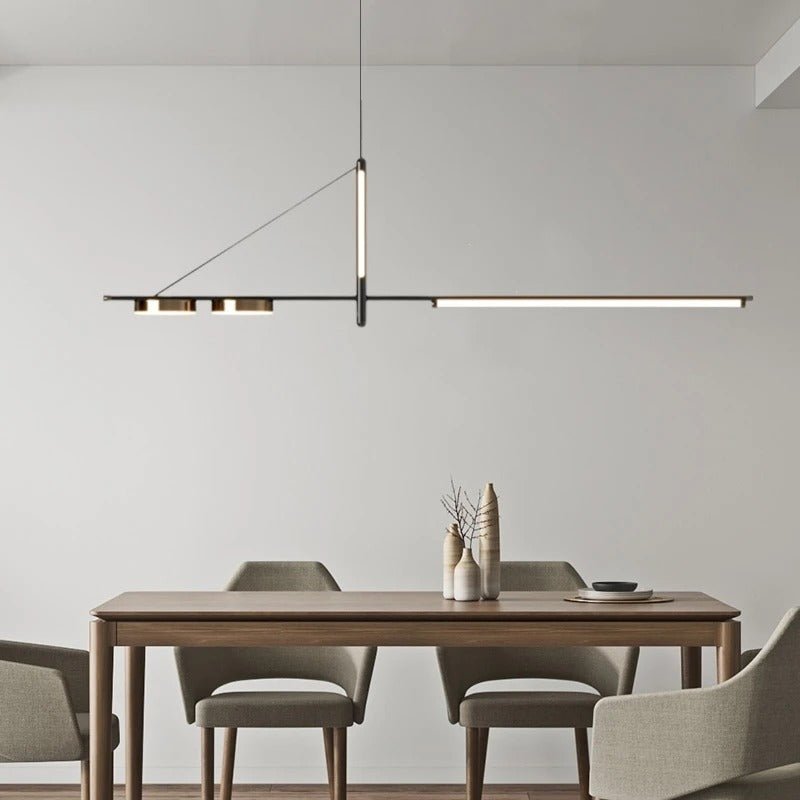 Clérachic black linear chandelier with LED bar and two brass-toned discs hung over a wooden dining table in a calm grey room.