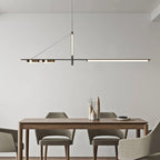 Clérachic black linear chandelier with LED bar and two brass-toned discs hung over a wooden dining table in a calm grey room.