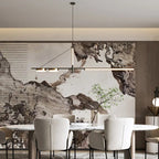 Clérachic black linear chandelier with warm LED bars over an oval marble dining table and cream chairs, before an ink-wash mural.