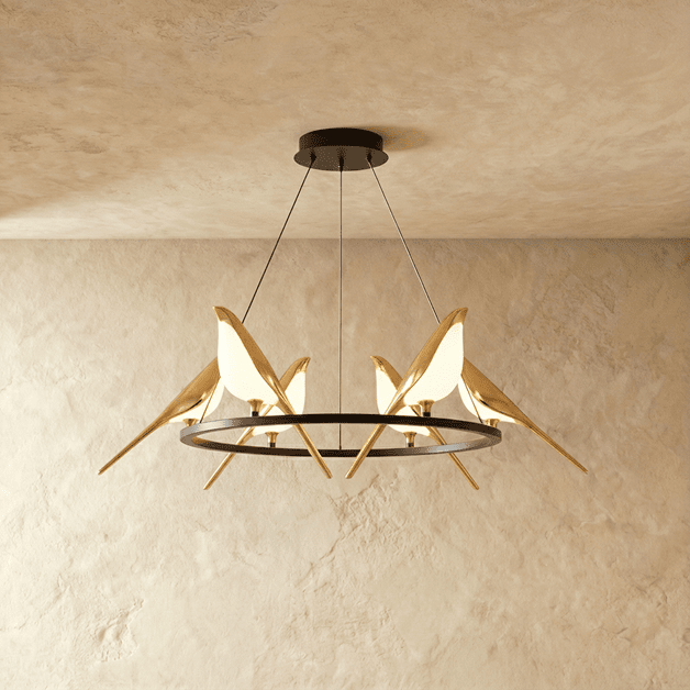Clérachic ring chandelier with gold bird figures whose bodies glow white, hung from a black canopy in a plaster-toned studio.