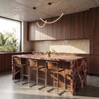 Clérachic curved LED arc chandelier glowing above a kitchen island with a red marble top, walnut cabinets and concrete ceiling
