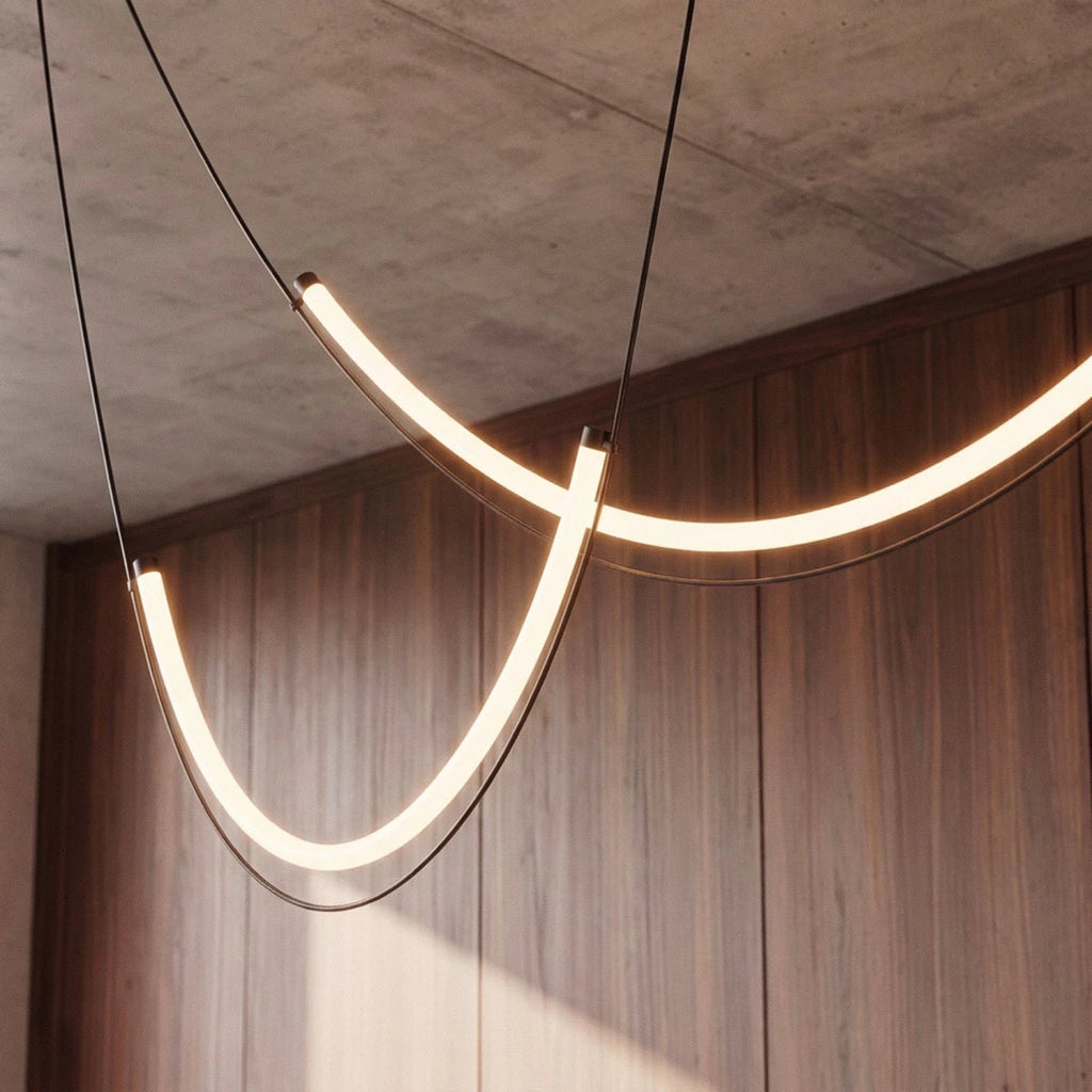 Close up of Clérachic curved LED arcs glowing warm white, with the black cables and metal end caps against walnut panelling