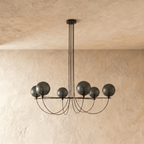 Clérachic six-globe chandelier unlit, showing dark smoky glass shades on a black iron armature with draped cords.