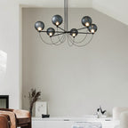 Clérachic black chandelier with smoky glass globes glowing in a pale living room above a white sideboard.