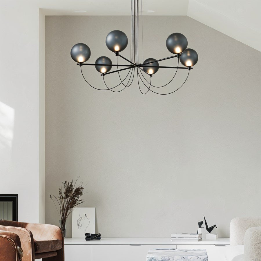 Clérachic black chandelier with smoky glass globes glowing in a pale living room above a white sideboard.