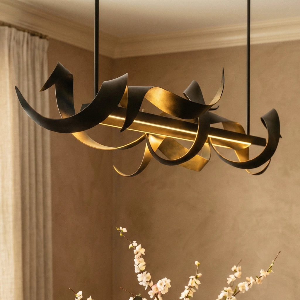 Clérachic close view of the black ribbon chandelier lit warm over a dining room, with blossom branches in the foreground.