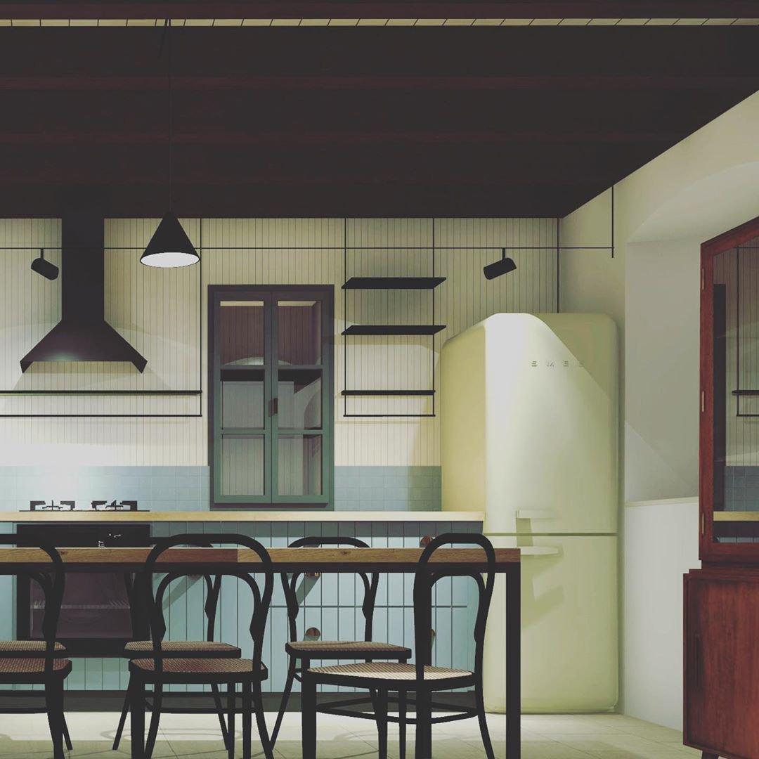 Black Clérachic cone pendant over a kitchen with cream cabinets, a pale green fridge and bentwood chairs at a long table.