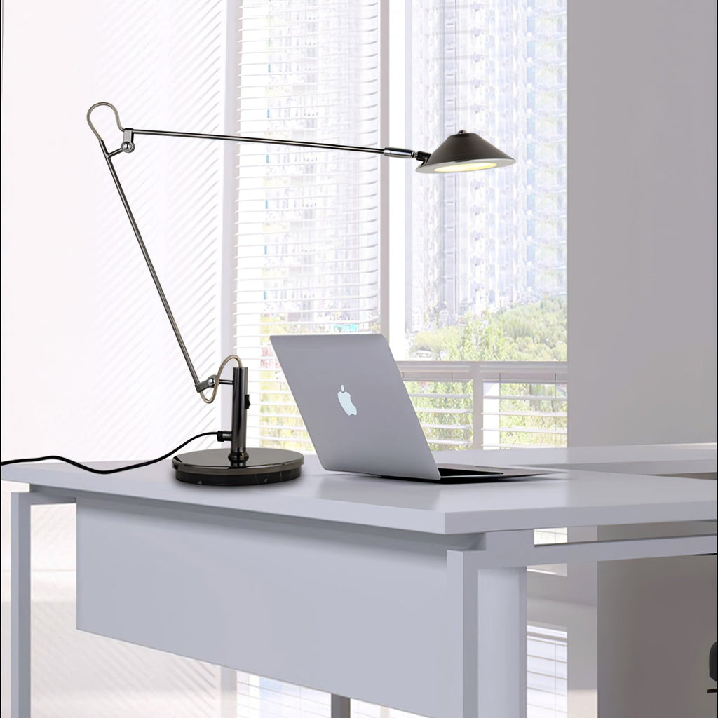 A Clérachic black arm lamp on a white desk, its lit shade reaching over a laptop, with a city view through the window.